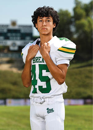 A young man wearing a white and black jersey with the number 14 on it. Description generated by AI