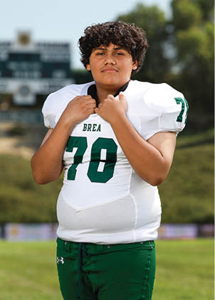 A young man wearing a white and black jersey with the number 14 on it. Description generated by AI