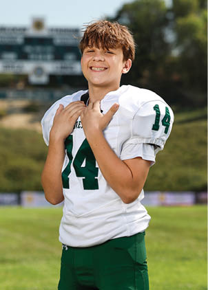 A young man wearing a white and black jersey with the number 14 on it. Description generated by AI