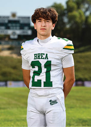 A young man wearing a white and black jersey with the number 14 on it. Description generated by AI