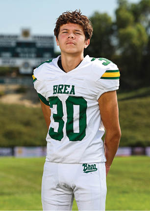 A young man wearing a white and black jersey with the number 14 on it. Description generated by AI