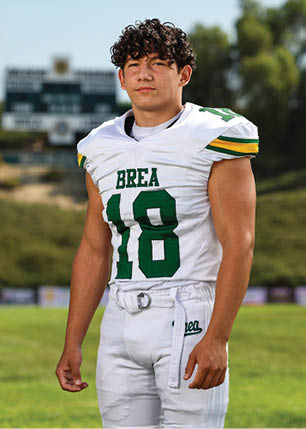 A young man wearing a white and black jersey with the number 14 on it. Description generated by AI