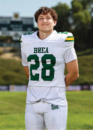 A young man wearing a white and black jersey with the number 14 on it. Description generated by AI