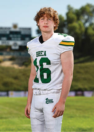 A young man wearing a white and black jersey with the number 14 on it. Description generated by AI