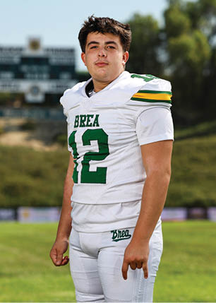 A young man wearing a white and black jersey with the number 14 on it. Description generated by AI