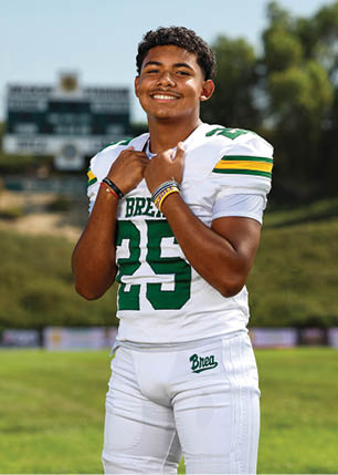 A young man wearing a white and black jersey with the number 14 on it. Description generated by AI