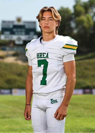 A young man wearing a white and black jersey with the number 14 on it. Description generated by AI