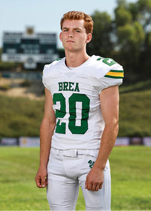 A young man wearing a white and black jersey with the number 14 on it. Description generated by AI