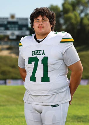A young man wearing a white and black jersey with the number 14 on it. Description generated by AI