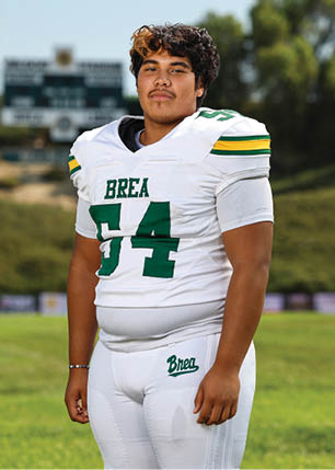 A young man wearing a white and black jersey with the number 14 on it. Description generated by AI