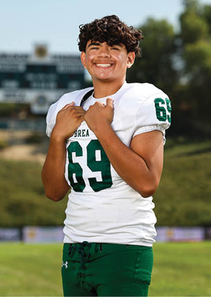 A young man wearing a white and black jersey with the number 14 on it. Description generated by AI