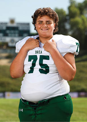 A young man wearing a white and black jersey with the number 14 on it. Description generated by AI