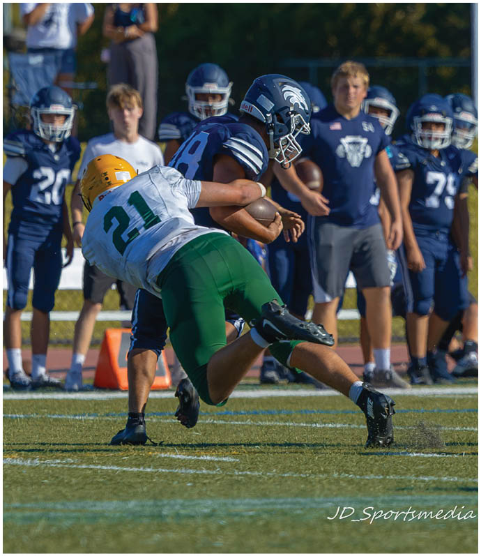 Three football players in blue and white uniforms running on a field. Description generated by AI