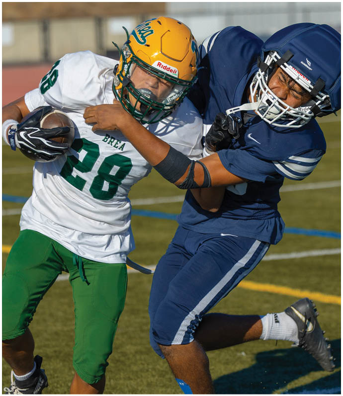 Three football players in blue and white uniforms running on a field. Description generated by AI
