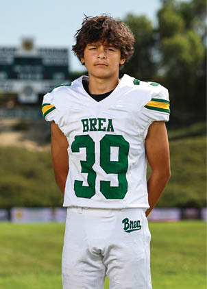 A young man wearing a white and black jersey with the number 14 on it. Description generated by AI
