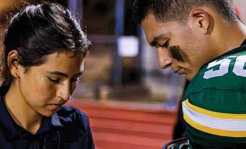 Two men wearing football uniforms are hugging each other on a field. AI generated content