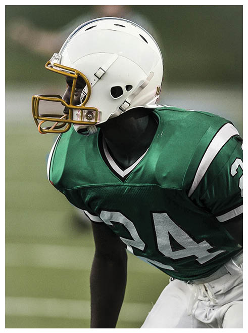A football player wearing a helmet and jersey with the number 24. Description generated by AI