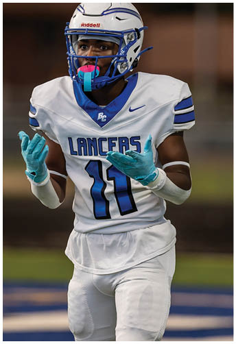 A person wearing a white football uniform with the number 11 and the word Lancers on the jersey is standing on a field with blue and white markings. Description generated by AI