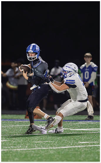 A person wearing a blue football helmet with a white stripe and the word “WEST" on the front is looking to the side against a dark background. Description generated by AI