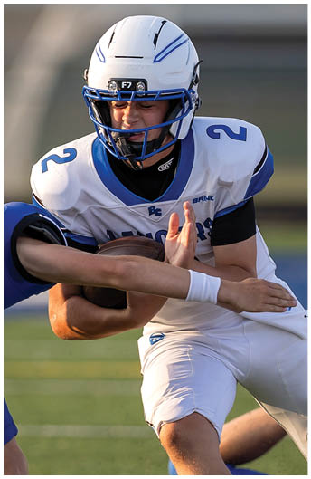A person wearing a white and blue football uniform and helmet is captured in action during a game. Description generated by AI