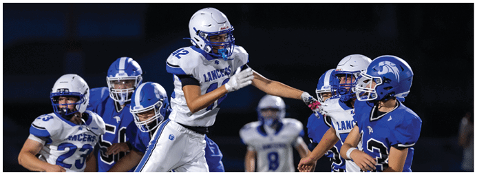 People wearing football helmets and uniforms are engaged in a game or practice on a field. Description generated by AI