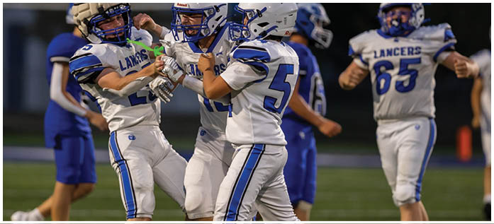People in football uniforms are celebrating on the field during a game at night. Description generated by AI