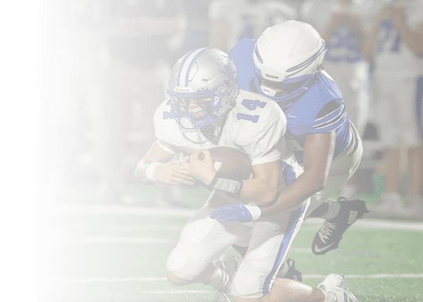Two people in football uniforms are engaged in a tackle, with one holding the football tightly while the other attempts to stop them. Description generated by AI