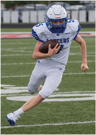 A person wearing a white and blue football uniform is running on a grassy field while holding a football tightly. Description generated by AI