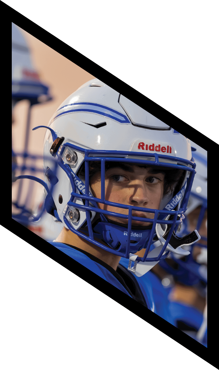 People wearing blue and white football helmets are lined up closely together, appearing focused and ready for action. Description generated by AI
