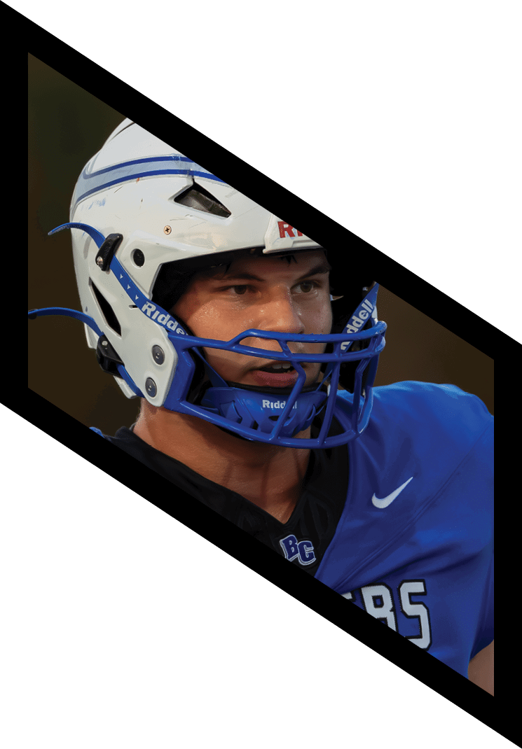 A person wearing a blue sports helmet and a blue and black jersey is shown in a close-up view. Description generated by AI