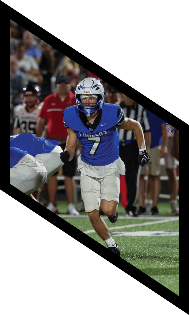 Several people in blue and white football uniforms are lined up on a field with one person running forward. Description generated by AI