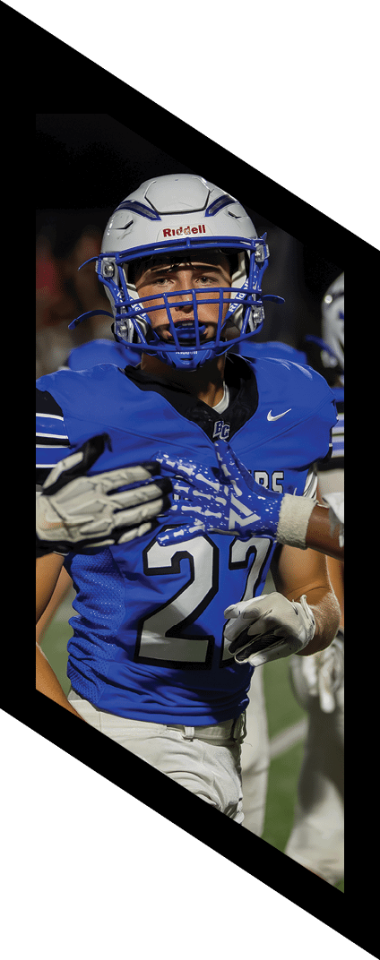 A person wearing a blue football helmet and blue jersey is focused and appears to be in action during a game. Description generated by AI
