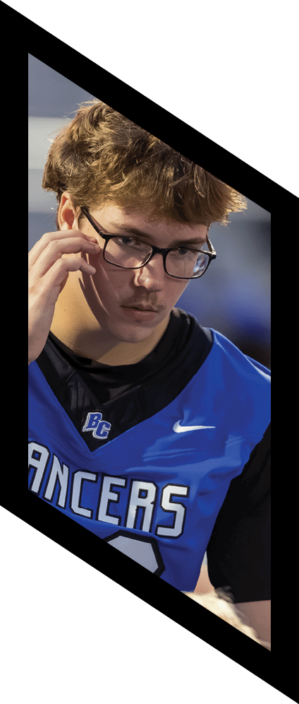A person wearing glasses and a blue sports jersey with the word LANCERS is focused and appears to be engaged in an activity. Description generated by AI