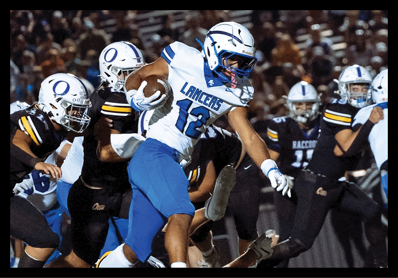 A person in a white and blue football uniform with the word LANCERS is running with a football while other players in white and black uniforms are in the background on a field with a crowd behind them. Description generated by AI