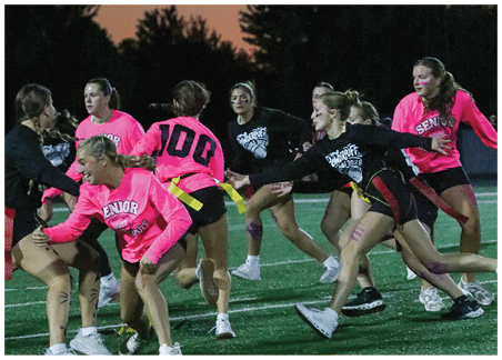 Two people are engaged in a flag football game with one person attempting to grab a yellow flag from the other’s waist. Description generated by AI