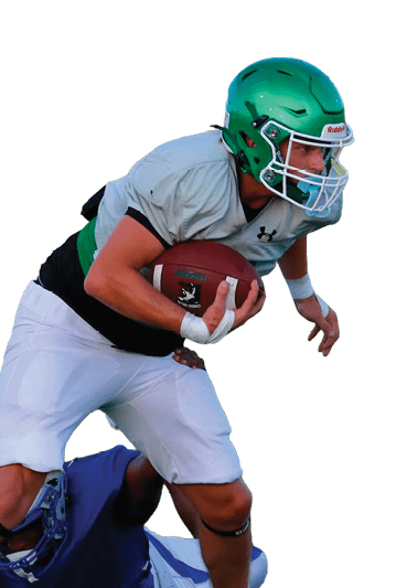 A person wearing a green helmet and white football uniform is running with a football while another person in a blue uniform is on the ground attempting to tackle them on a football field. Descripci n generada con IA