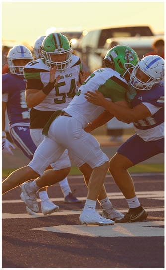 Two people in football uniforms and helmets are engaged in a close physical tackle on a football field during a game. Descripci n generada con IA