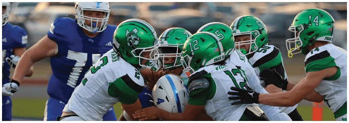 Several people in green and white football uniforms are tackling a person in a blue and white uniform on a football field. Descripci n generada con IA