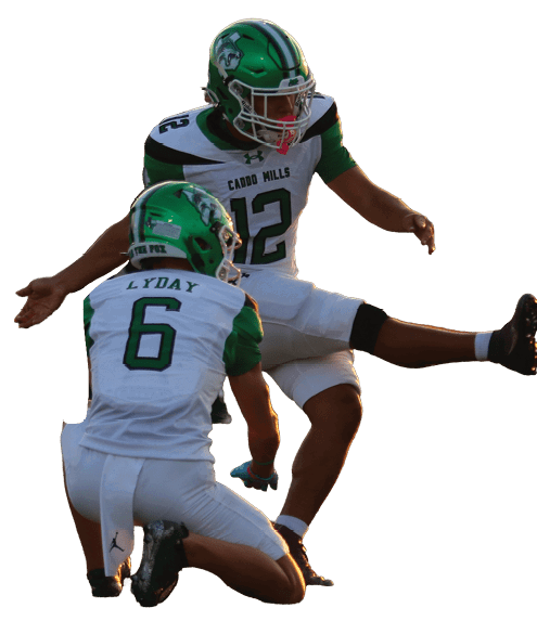 Two people in green and white football uniforms are on a field with one holding the ball in place while the other kicks it. Descripci n generada con IA
