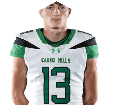 A person stands with hands behind their back wearing a green and white football uniform with the number 13 and the words “Caddo Mills" on the jersey. Descripci n generada con IA