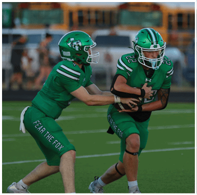 A person wearing a green football uniform and helmet is running while holding a football during a game. Descripci n generada con IA