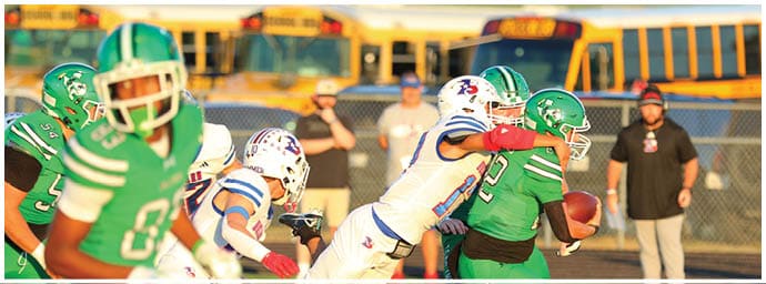 People in football uniforms are actively playing on a field with one person holding the ball while others attempt to tackle or block. Descripci n generada con IA