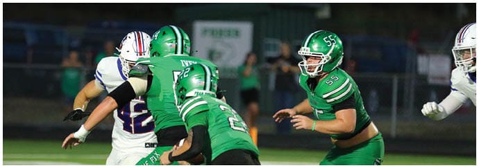 People wearing green and white football uniforms are engaged in a play on a football field. Descripci n generada con IA