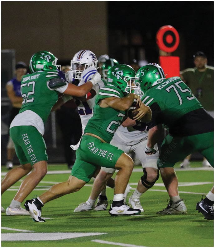 People in green and white football uniforms are engaged in a play on a football field under stadium lights. Descripci n generada con IA