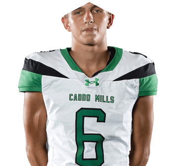 A person stands with hands behind their back wearing a white and green sports uniform with the number six and the words “Caddo Hills" on the front. Descripci n generada con IA