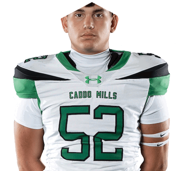 A person wearing a white and green football jersey with the number 52 and the words Caddo Mills on the front. Descripci n generada con IA
