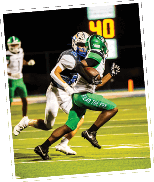 Two people in football uniforms are running on a field with one person holding a football near a goalpost and a scoreboard showing the number 40 in the background. Descripci n generada con IA