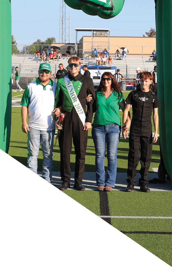 Estructura inflable verde con la forma del estado de Texas, un logo de un zorro y la palabra “FOXES" con personas caminando debajo en un d a soleado. Descripci n generada con IA