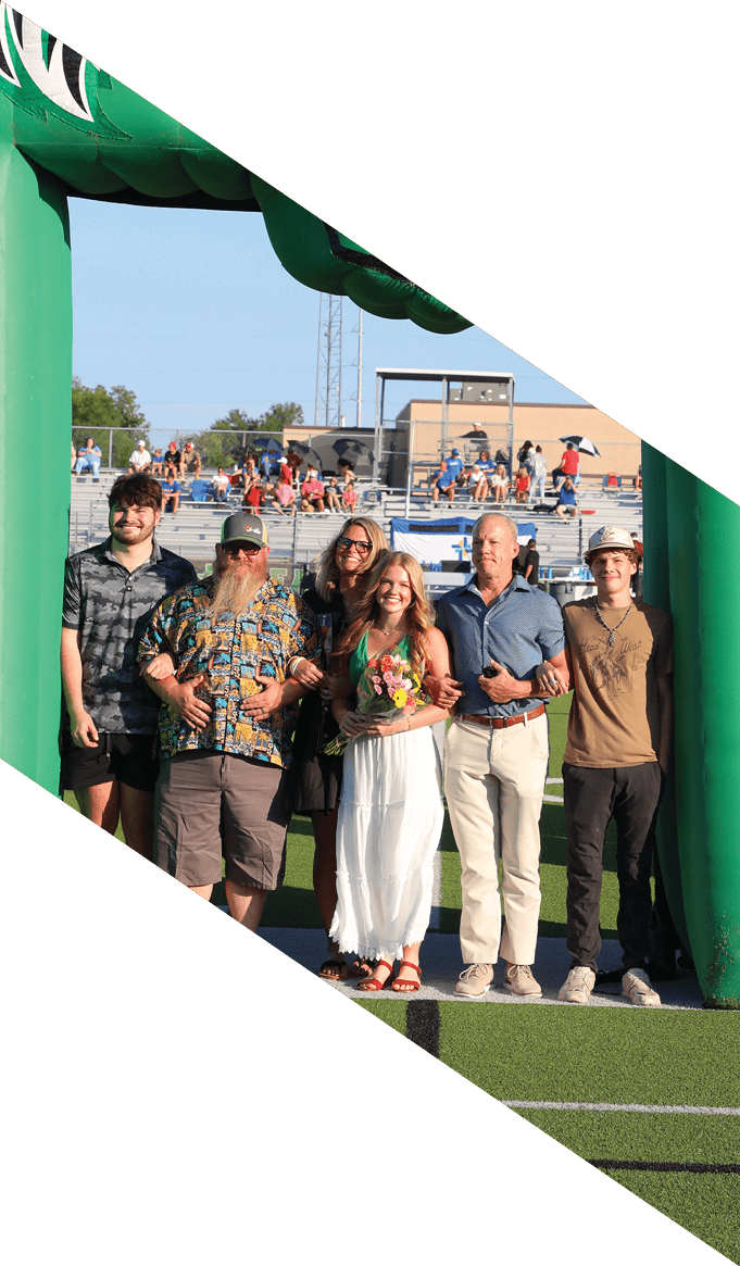 Un grupo de personas sonrientes posan juntas en un campo deportivo con gradas y espectadores al fondo, una persona sostiene un ramo de flores. Descripci n generada con IA