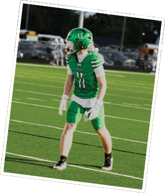 Two people in green and white football uniforms with helmets are on a field, one flexing their arms while the other stands nearby. Descripci n generada con IA